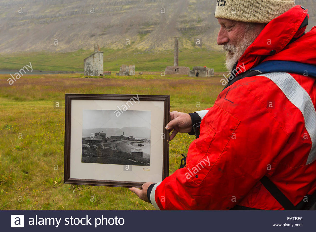 Ein Mann hält ein schwarz-weiß Foto einer historischen Walfang-Station. Stockfoto