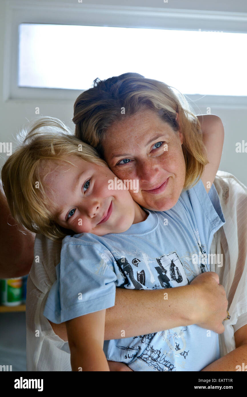 Eine Mutter umarmt ihren Sohn, wie er an seinem ersten Tag in der Schule bereitet. Stockfoto