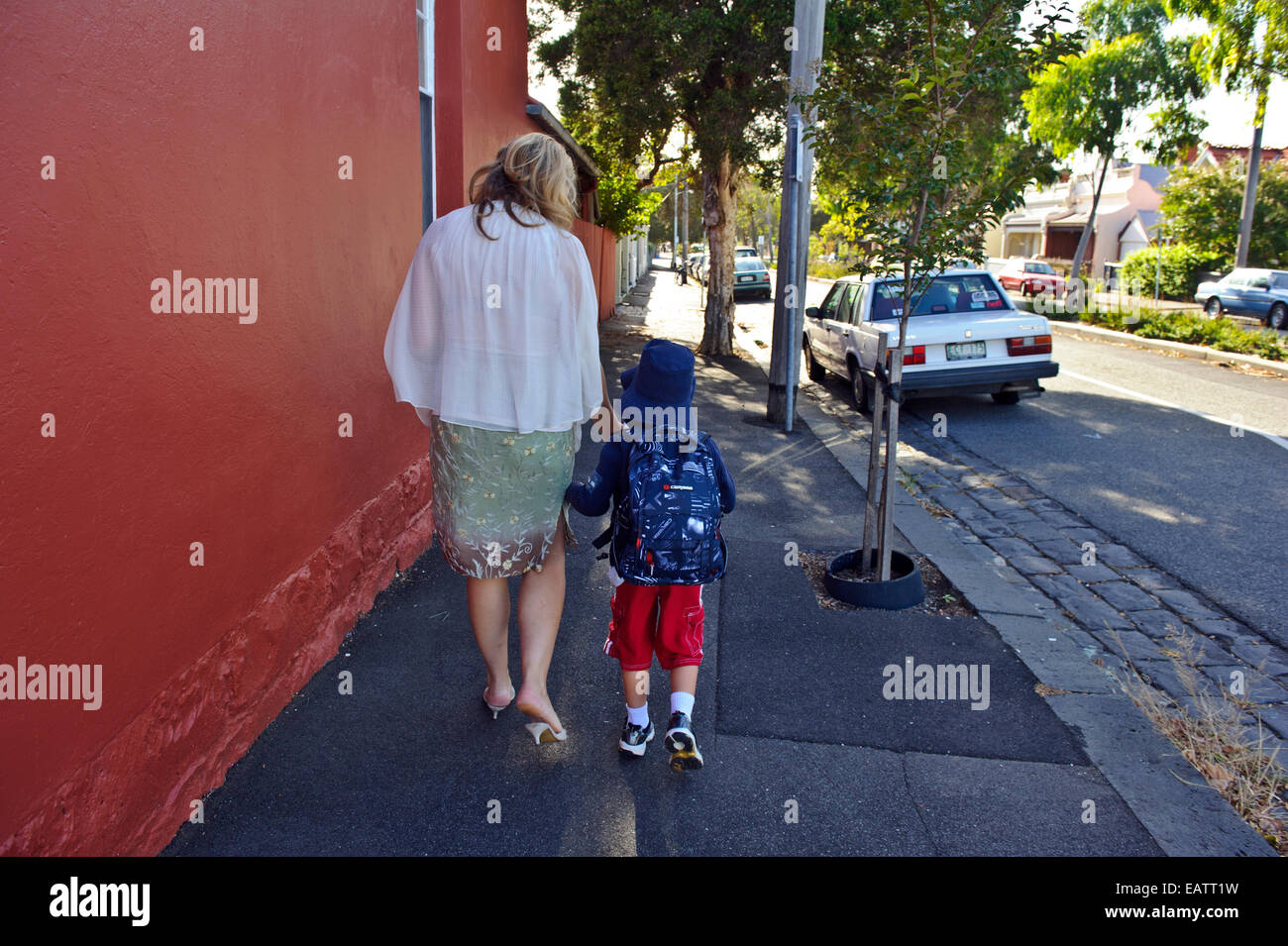 Eine Mutter geht mit ihrem Sohn auf dem Weg zu seinem ersten Tag der Schule. Stockfoto