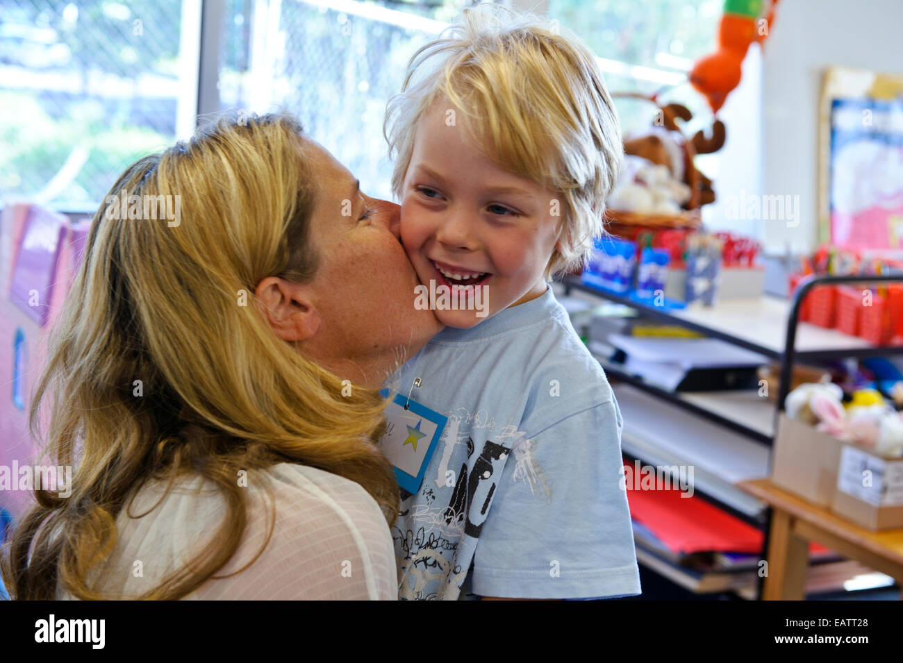 Eine Mutter küsst eine junge Abschied auf seinen ersten Schultag. Stockfoto