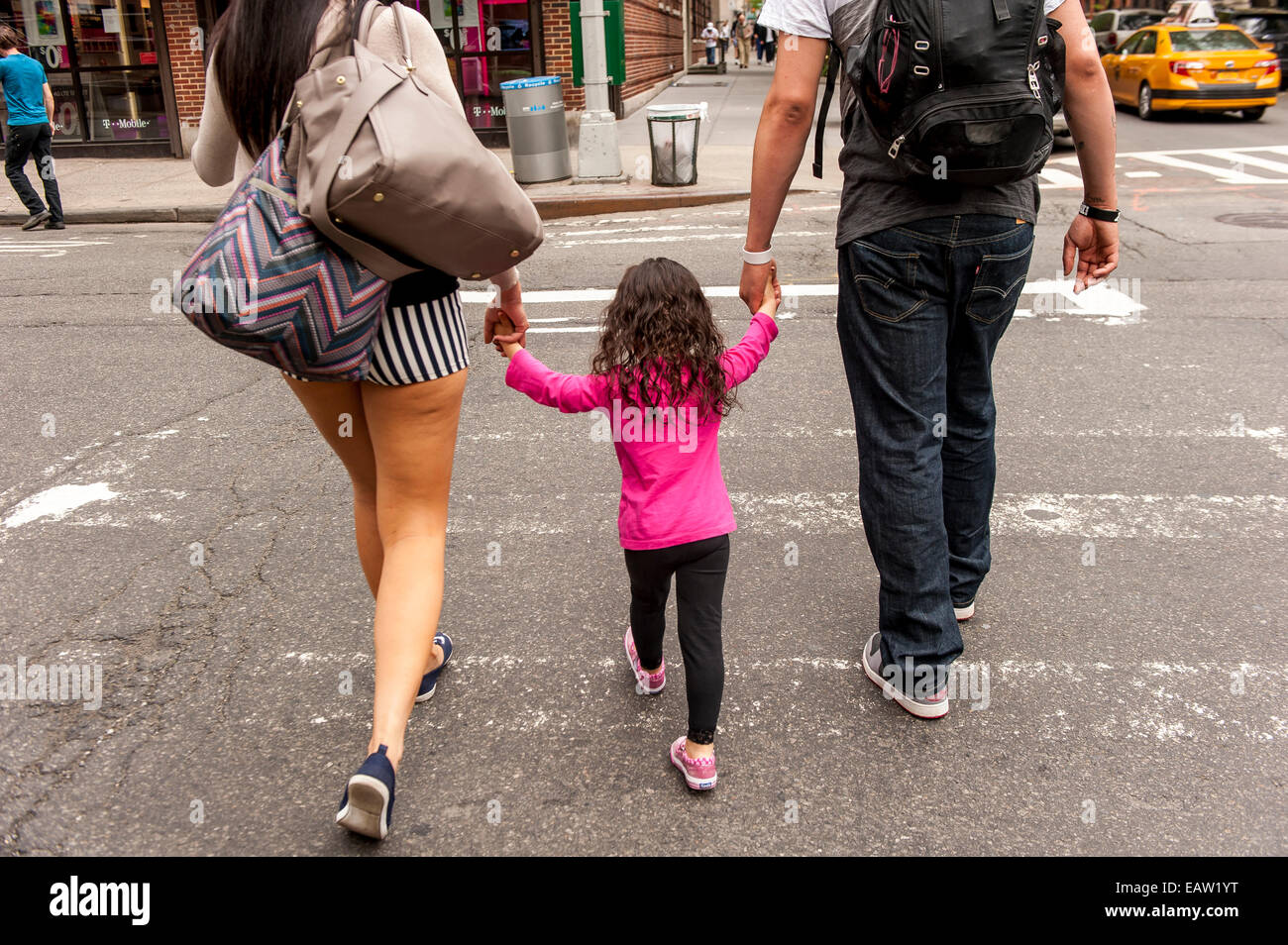 Mutter und Vater Händchen ihres kleinen Mädchens zwischen überqueren einer Straße in New York. Stockfoto