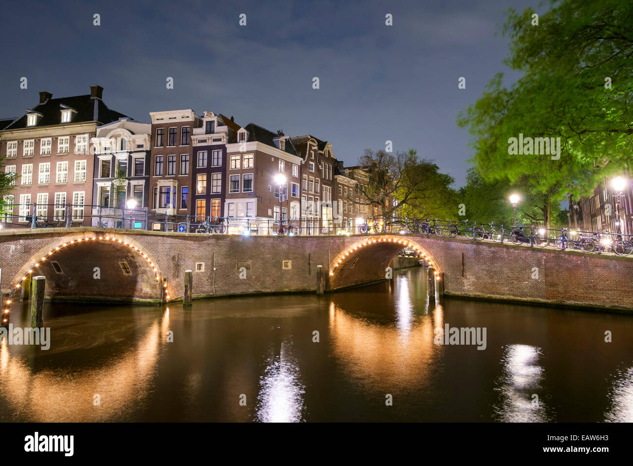 Gebäude und Bogenbrücken an der Kreuzung der Herengracht und Reguliersgracht bei Nacht, Amsterdam, Nordholland, Niederlande Stockfoto