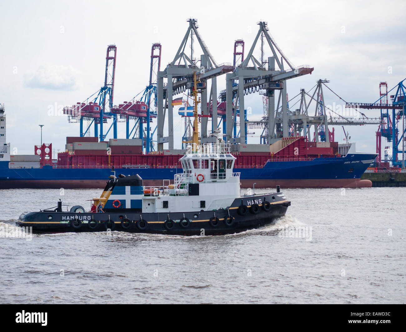 Ein Schlepper ist durch Ladung Kräne der Hamburger Burchardkai Container terminal vorbeigehen eine Frachtschiff im Hintergrund geladen wird. Stockfoto