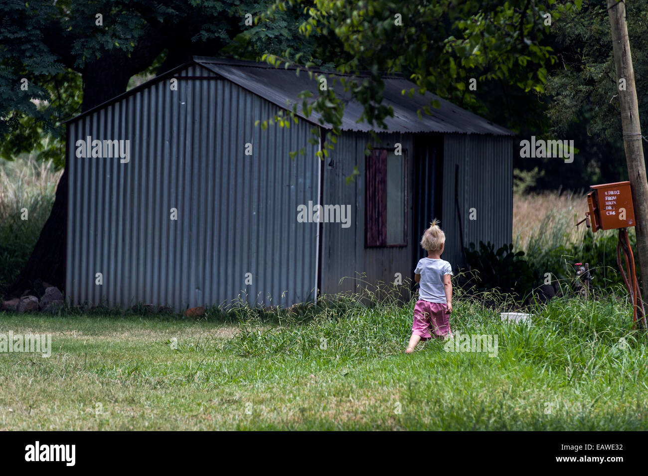 Ein kleines Mädchen erkundet ihr vertriebenen Gemeinschaft Gartenhaus Häuser. Stockfoto