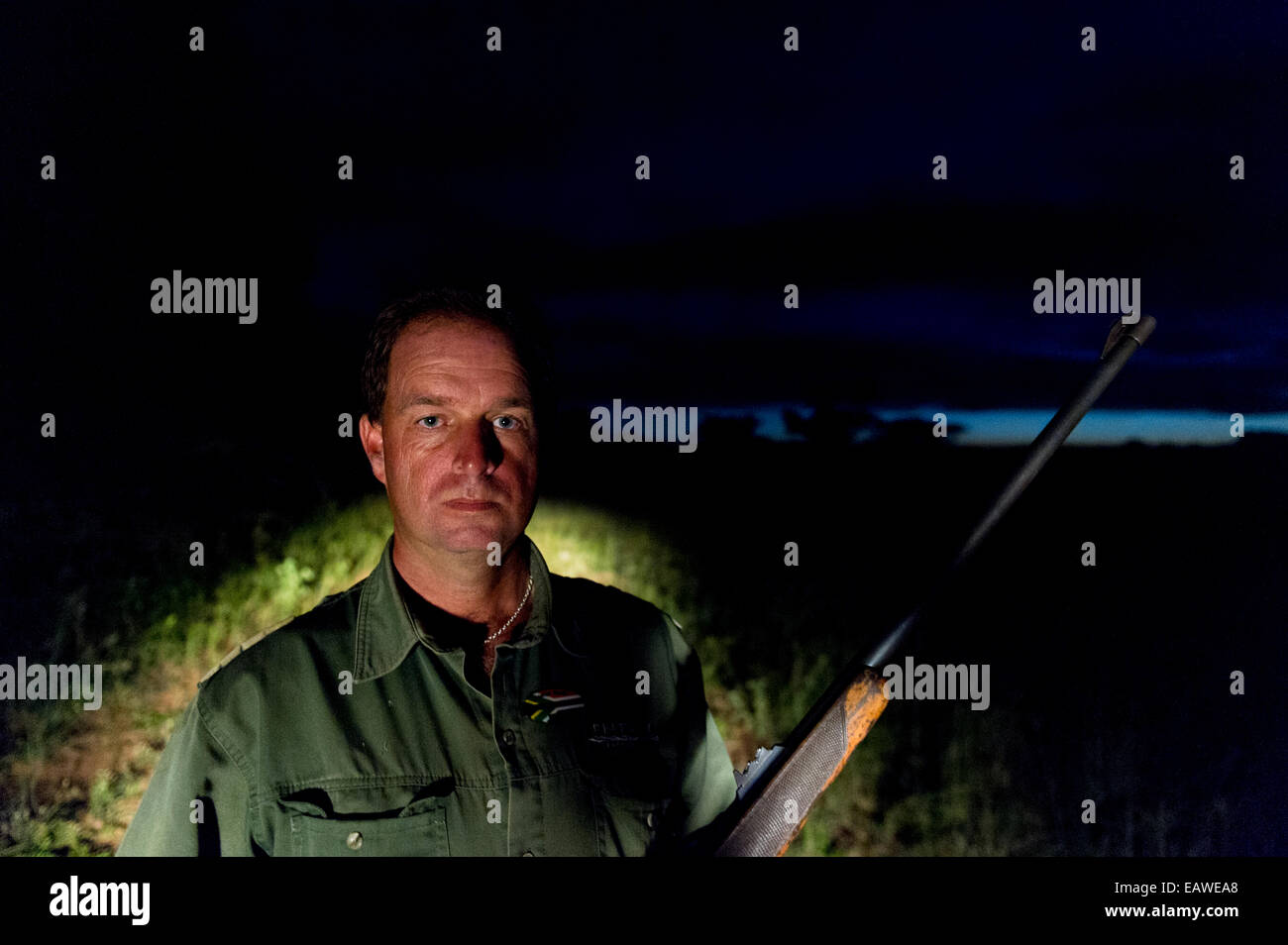 Ein Nationalpark-Ranger mit seinem Gewehr Patrouillen die Savanne in der Nacht. Stockfoto