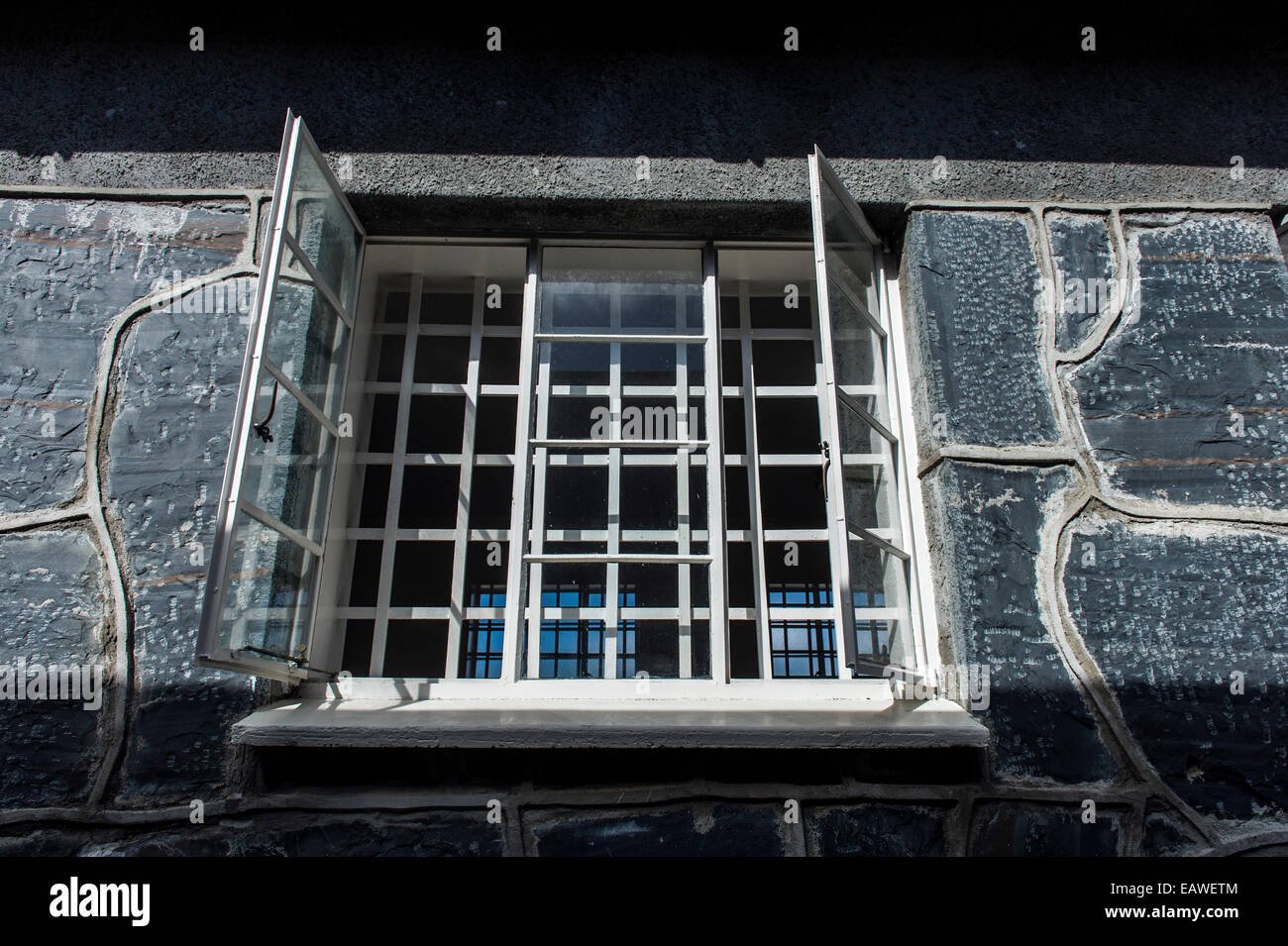 Stahlstäbe schließen Sie ein Fenster in einen grauen Stein Gefängnismauer. Stockfoto