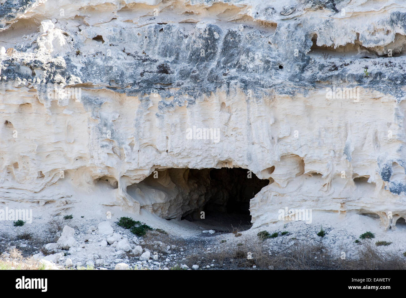 Ein höhlenartige Tunneleingang führt zu einem Gefängnis Kalksteinbruch in einer Felswand. Stockfoto