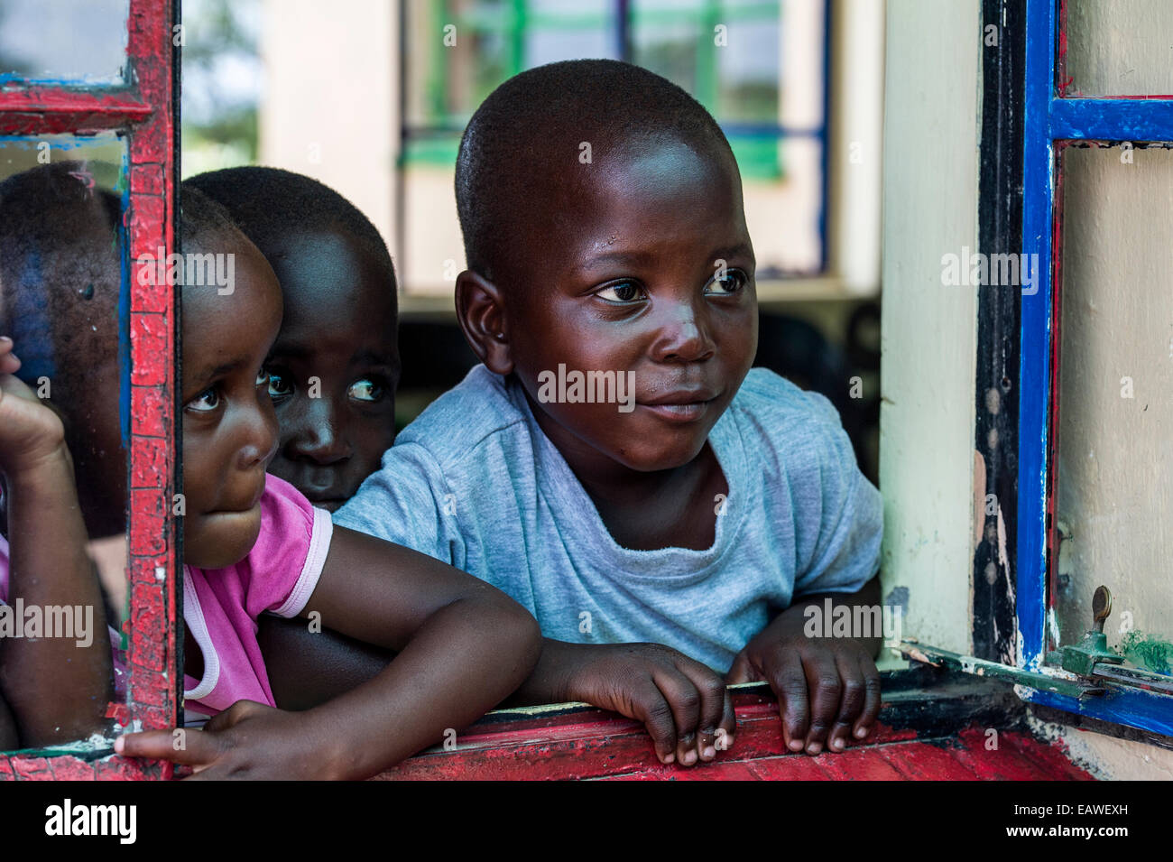 Kinder schauen aus dem Klassenzimmer-Fenster in einer kleinen afrikanischen Schule. Stockfoto