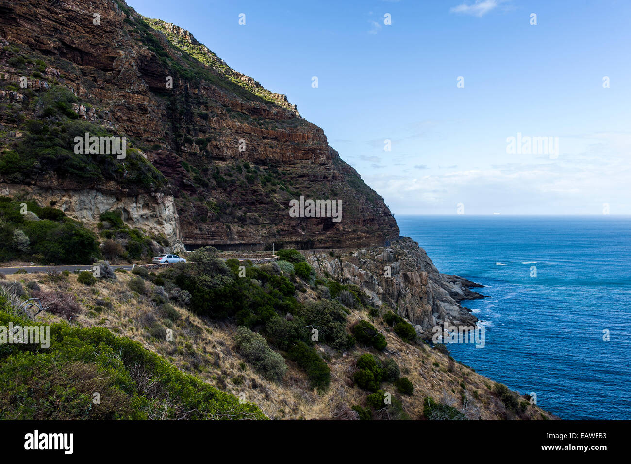 Ein Auto fährt auf eine Küstenstraße zwischen steilen Klippen und das Meer. Stockfoto