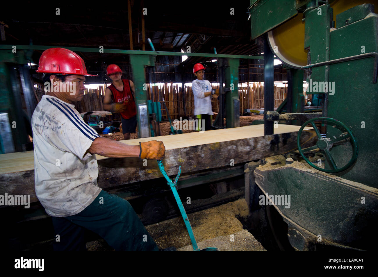 Ein Arbeiter betreibt eine Bandsäge, die Rinde von einem Amazon Rainforest Baum in einer Protokollierung Mühle. Stockfoto