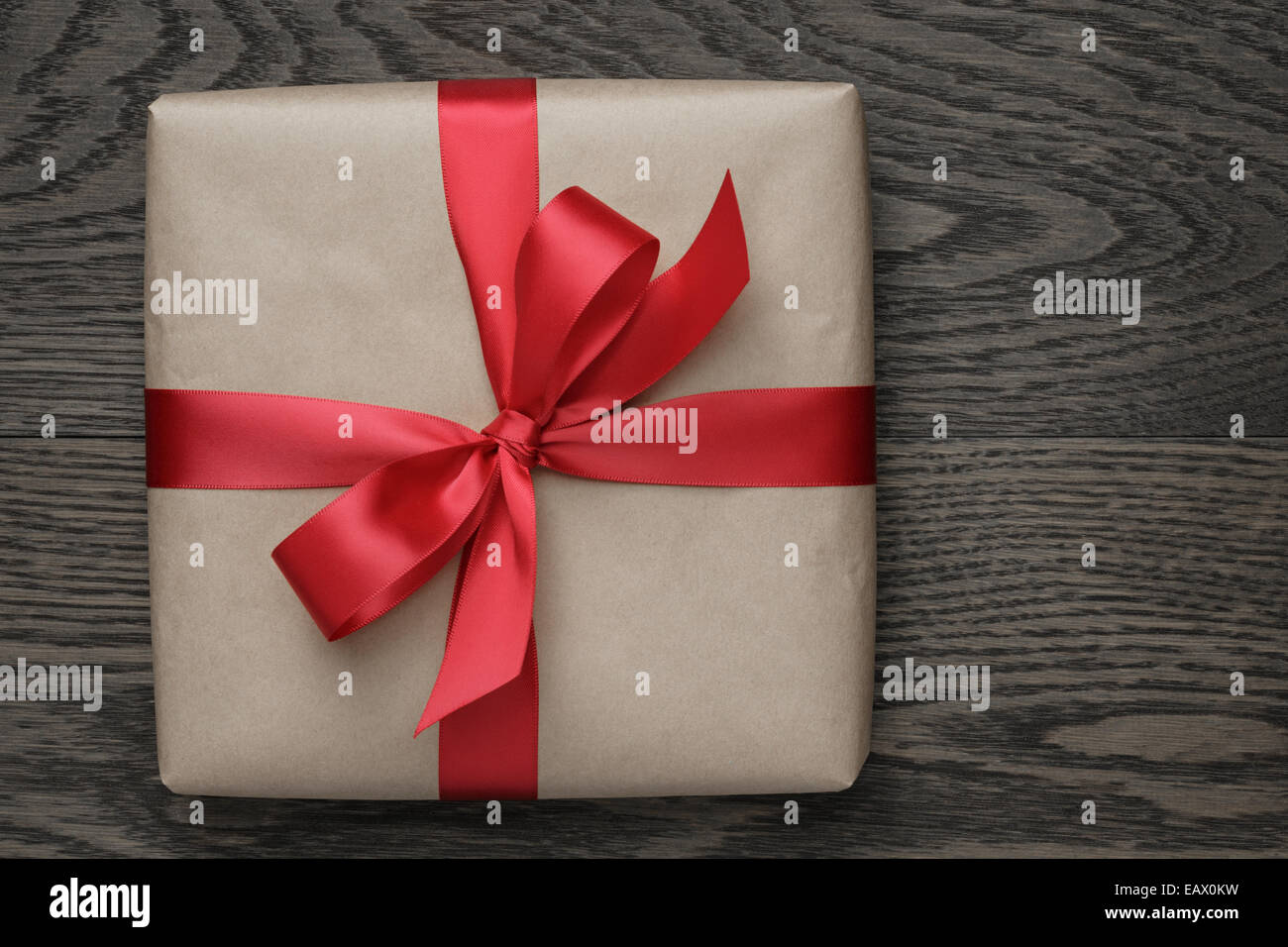 braune Geschenkbox mit roter Schleife auf Holztisch, Ansicht von oben Stockfoto