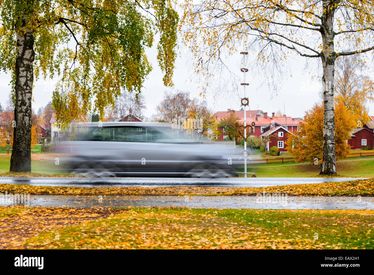 Auto bewegt sich mit Geschwindigkeit auf einer nassen Straße in Herbst Stockfoto
