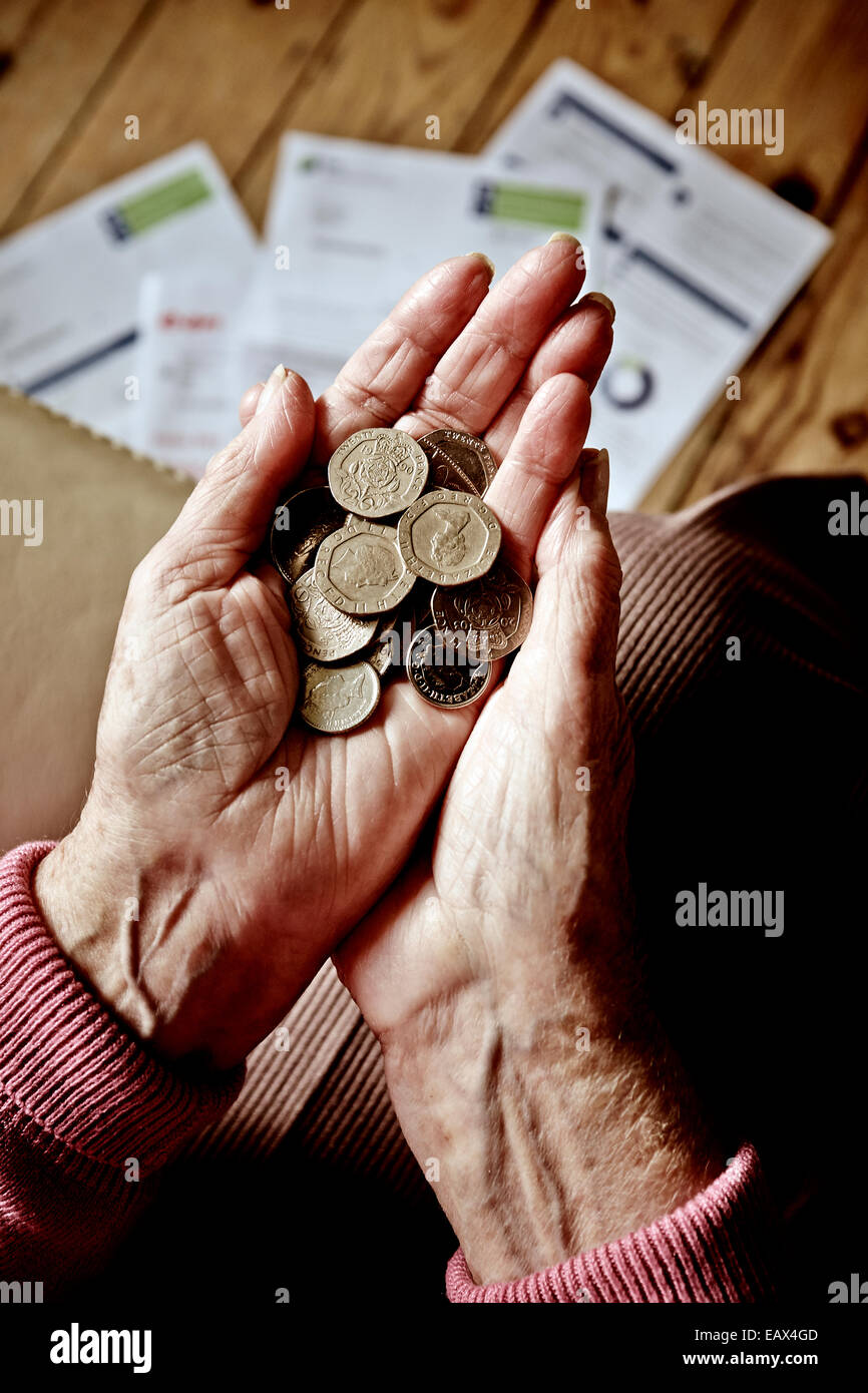 Rentner, die auf Geld in den Händen und Stromrechnungen auf dem Boden - Treibstoffarmut - Budget-Budgetierung - Haushalt Rechnungen Rente Stockfoto