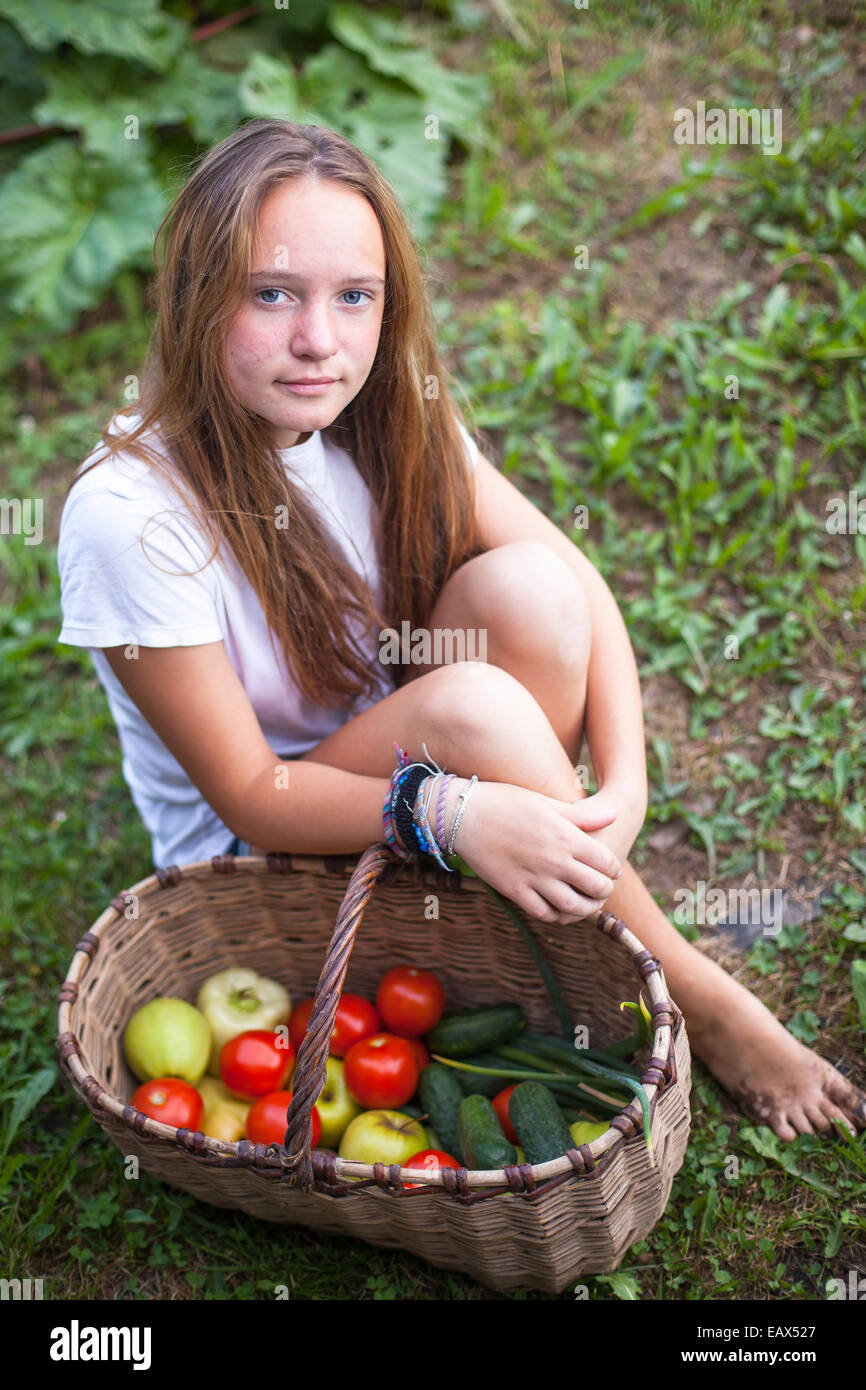 Teenager-Mädchen sitzen mit einem Korb voller Gemüse. Stockfoto
