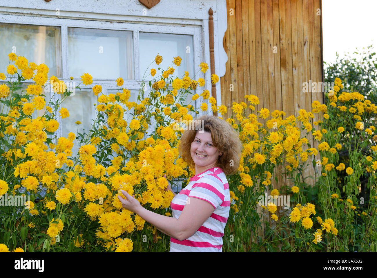 Frau mittleren Alters Fürsorge für Blumen in der Nähe des Hauses Stockfoto