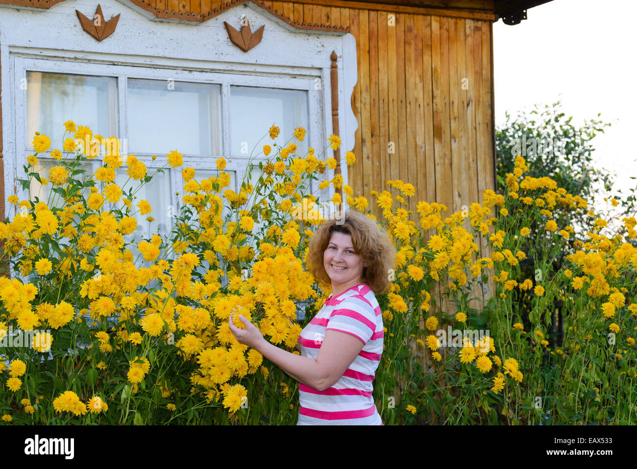 Frau mittleren Alters Fürsorge für Blumen in der Nähe des Hauses Stockfoto