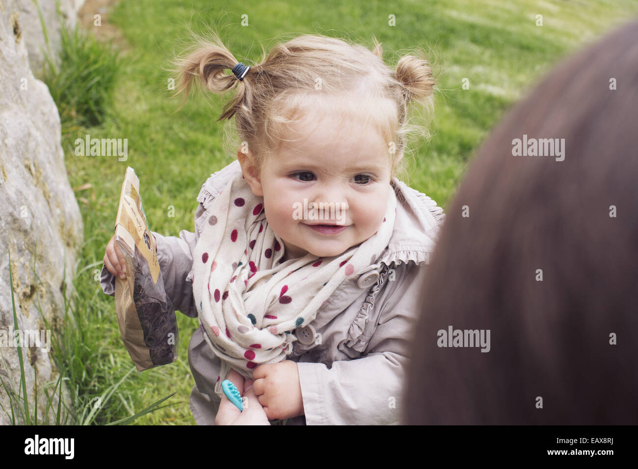 Baby Mädchen im Freien, Beutel mit Snacks in der hand Stockfoto