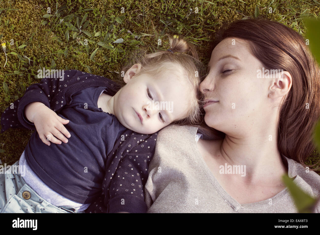 Mutter und Baby Mädchen Nickerchen auf dem Rasen Stockfoto