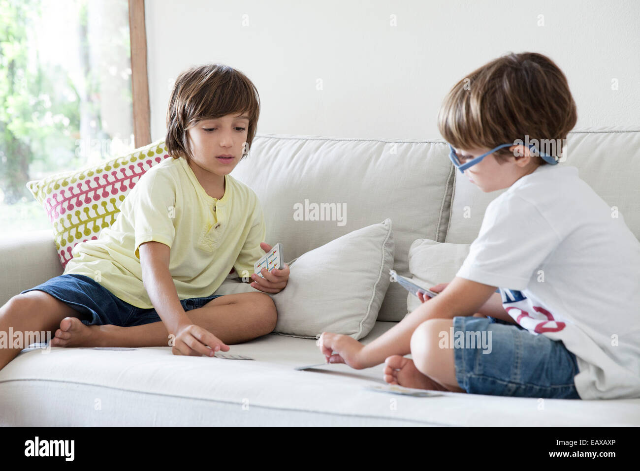 Jungen sitzen auf Sofa Spielkarten Stockfoto