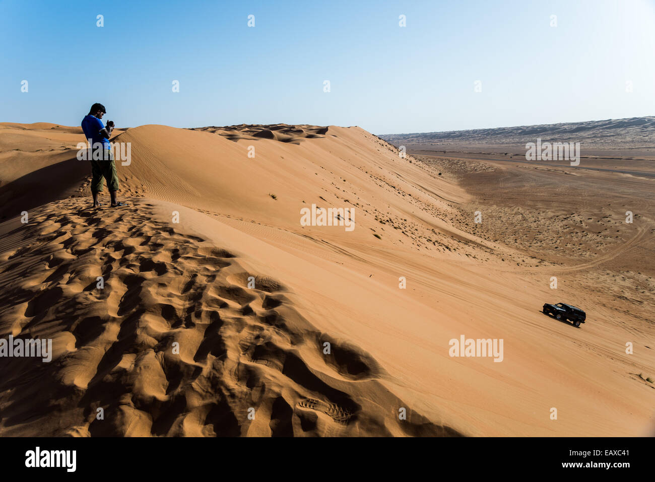 Ein junger Mann Videoaufzeichnung einen Allrad-Antrieb-Jeep fahren über Sanddünen in der Wüste von Oman. Stockfoto