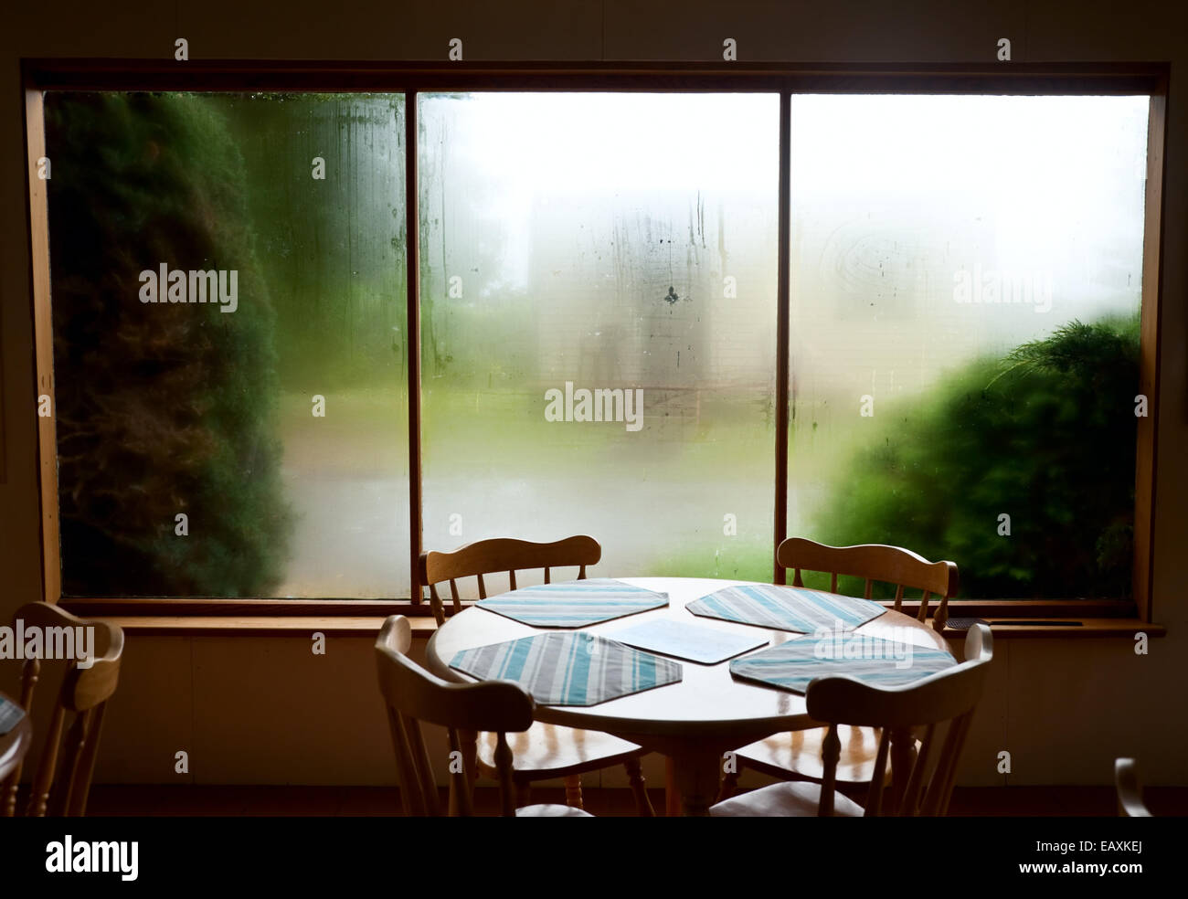 Leere Tabelle und Stühle gegen beschlagene Fenster im lässigen bistro Stockfoto