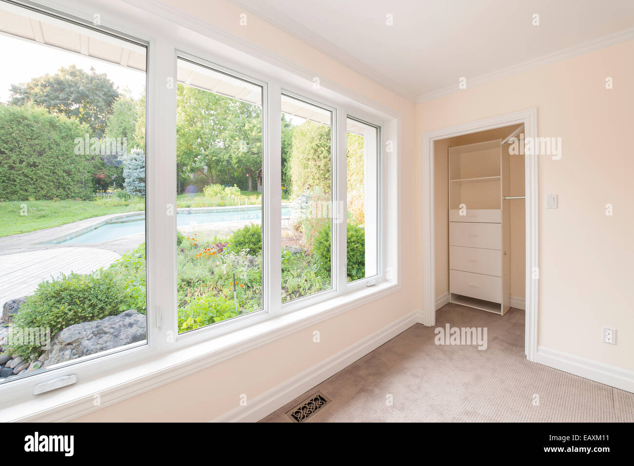 Große Fenster in leere Schlafzimmer schauen auf Sommer Hinterhof mit Garten und Wohn- Stockfoto