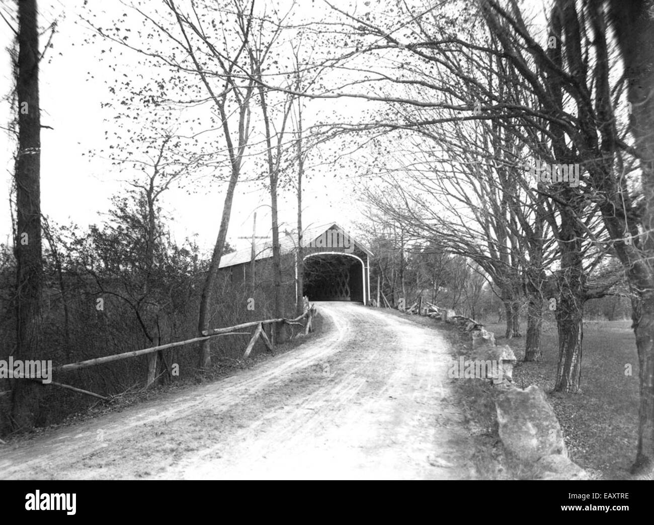 Dieses Bild zeigt eine historische überdachte Brücke in Cheshire County mit einer Steinmauer als malerische Kulisse. Die überdachte Brücke, die oft im ländlichen Neuengland zu sehen ist, stellt ein wichtiges architektonisches Merkmal aus dem 19. Jahrhundert dar. Stockfoto