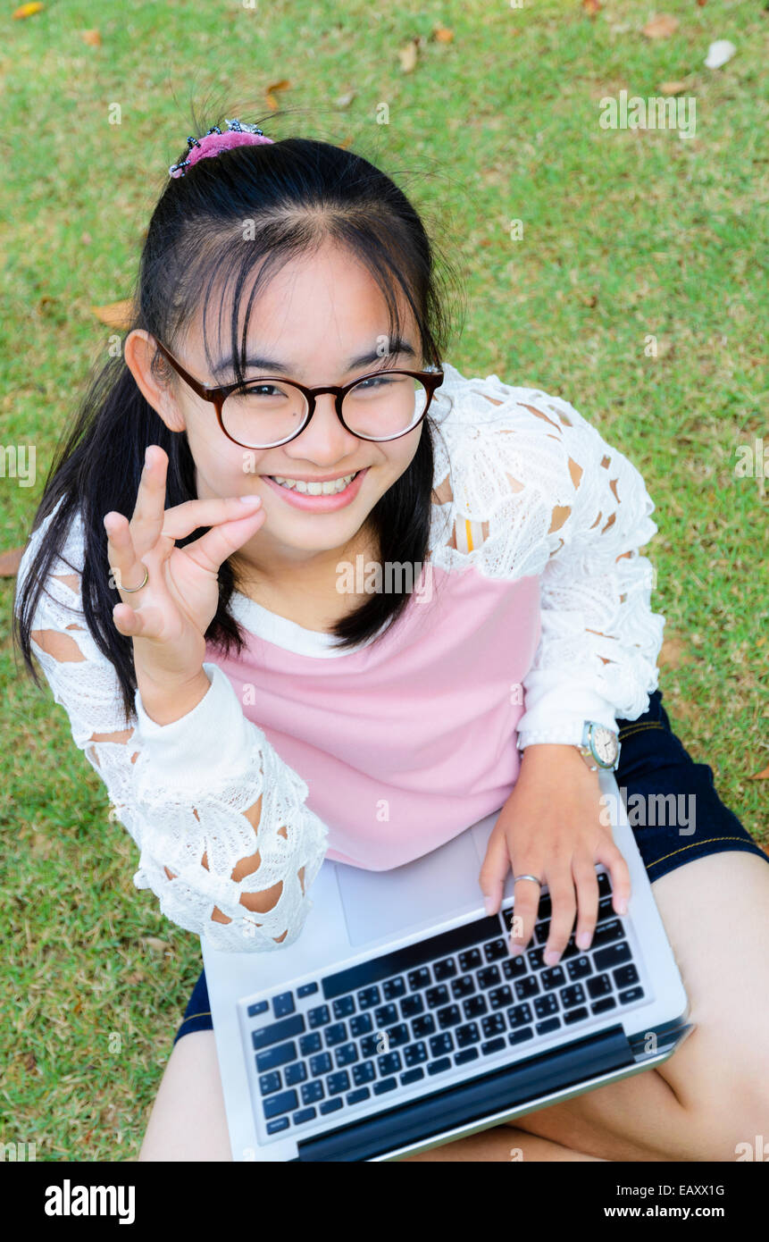 Schöne Mädchen ist glücklich mit einem Laptop auf Rasen im park Stockfoto