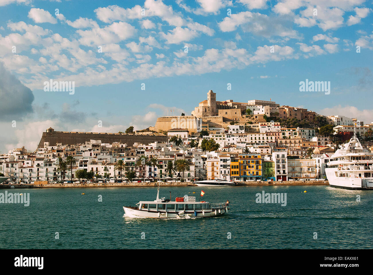 Panorama der Altstadt von Ibiza, der UNESCO und der Blick auf den Hafen vom Meer mit einem kleinen Boot für Touristen Stockfoto