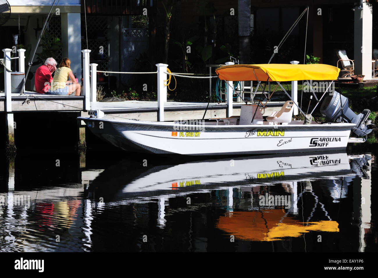 Ein paar sitzt auf einem Dock in der Nähe von ihrem Boot festgemacht an einem Kanal, Homosassa, Florida Stockfoto