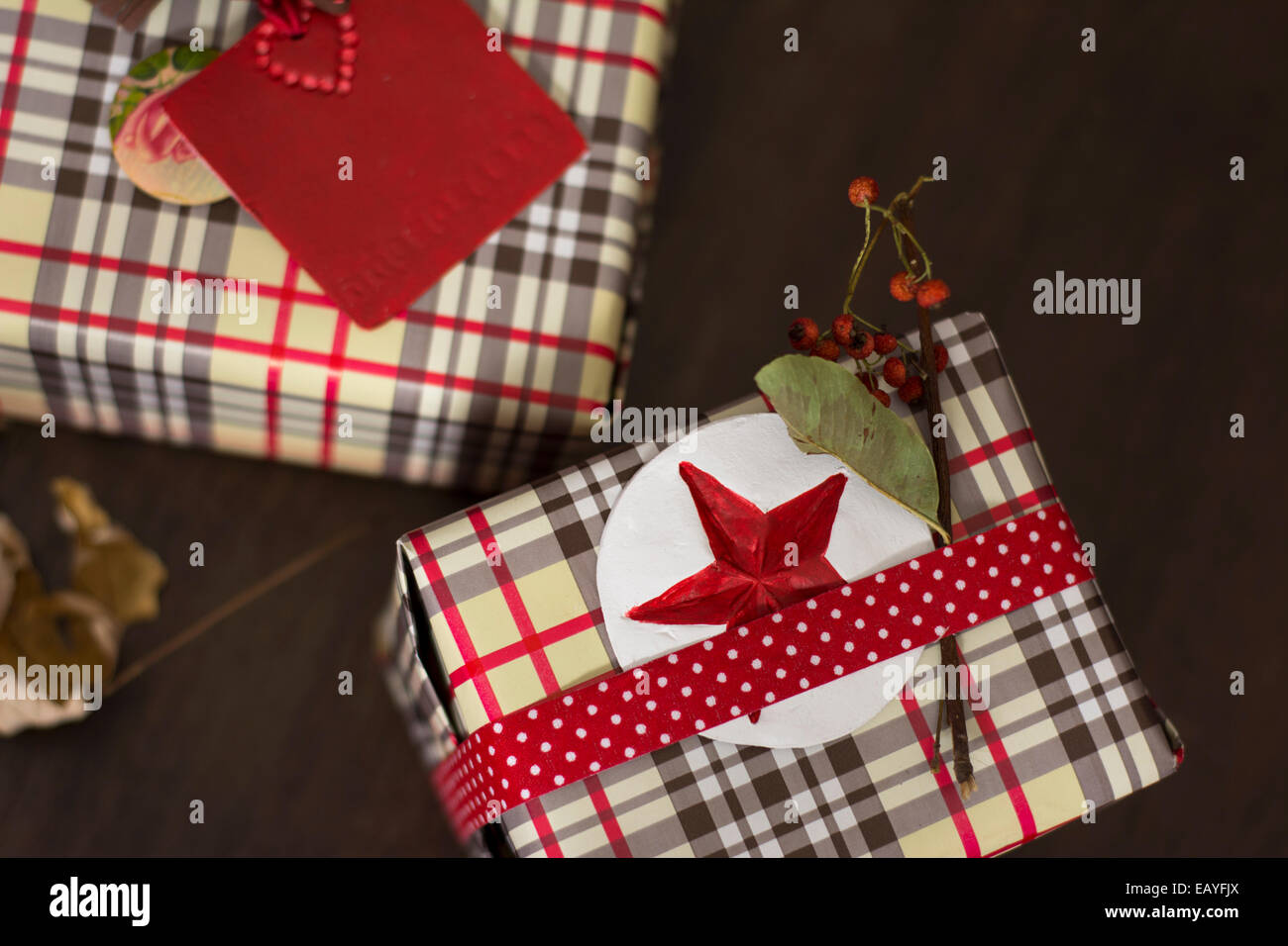 Geschenke in karierten Papier eingewickelt und gepunktete Band mit roten Sterne Aufkleber auf hölzernen Hintergrund Stockfoto