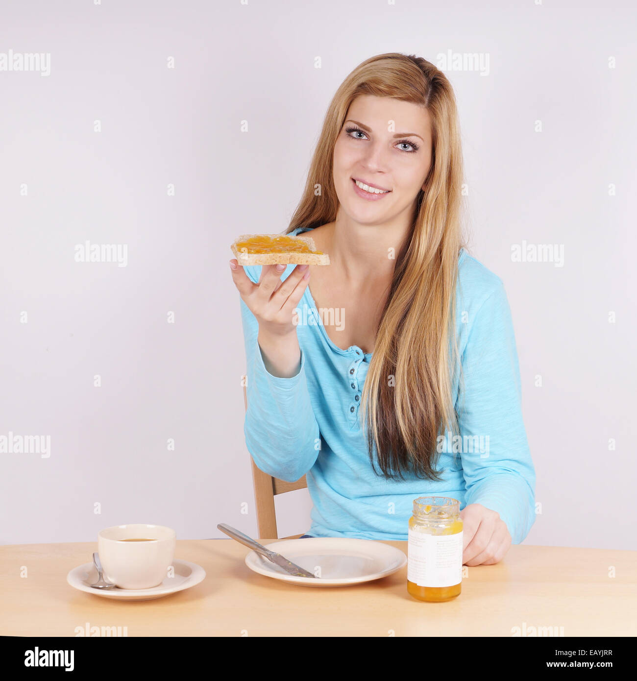 junge Frau beim Frühstück mit Toast, Marmelade und Kaffee Stockfoto