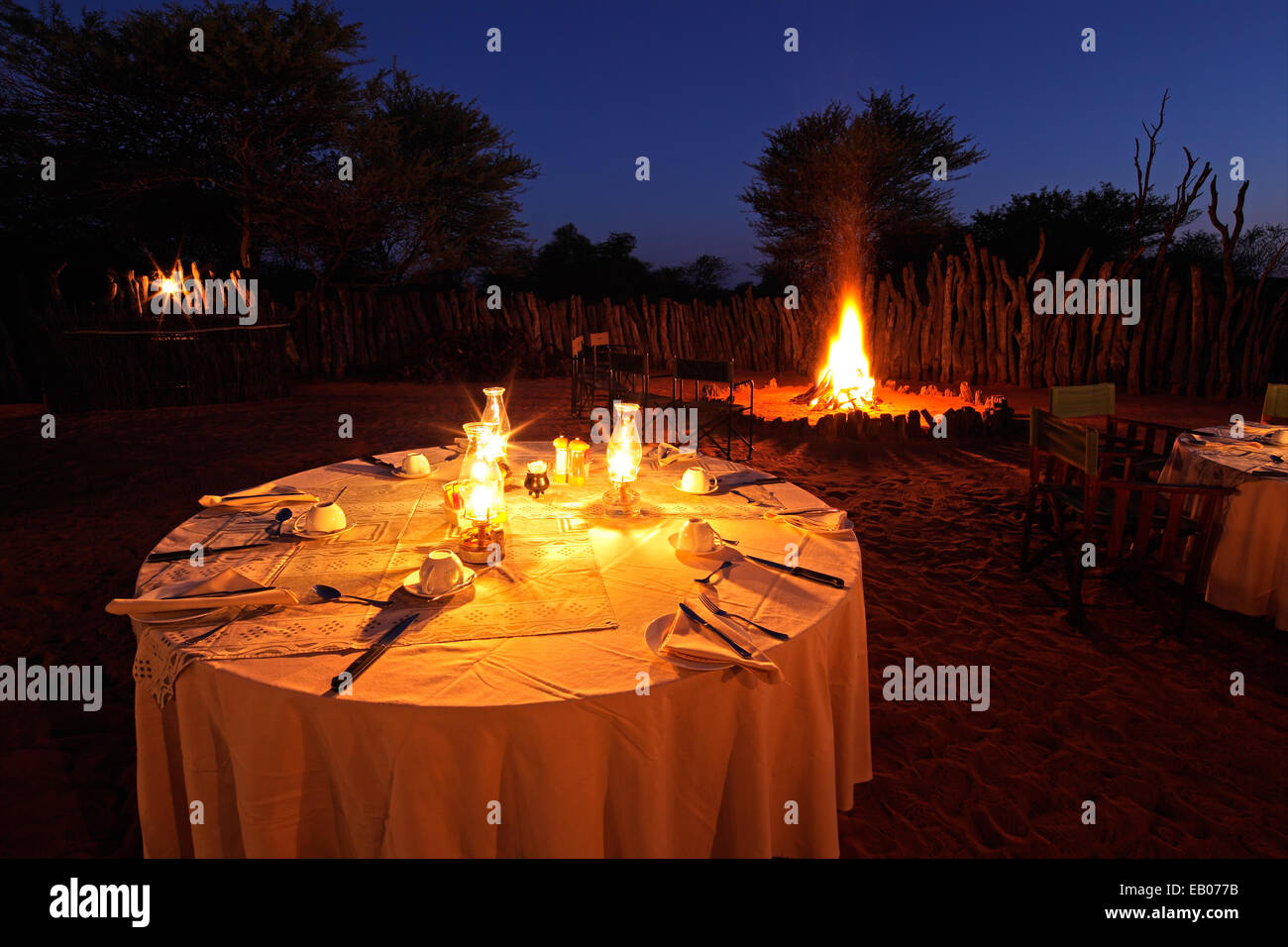 Nächtlichen Lagerfeuer und dekorierten Tisch für Outdoor-Safari catering Stockfoto