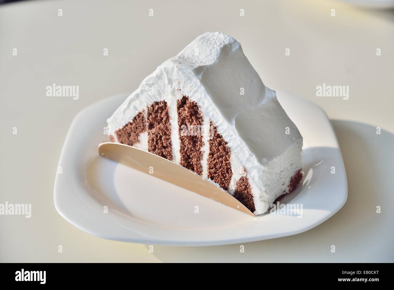 Schokoladenkuchen mit weißen Creme auf einem weißen Tisch Stockfoto