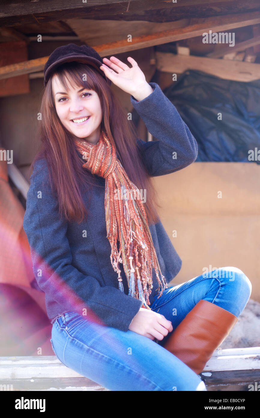 Fröhliches Mädchen in einer Kappe sitzen auf einer Bank Stockfoto