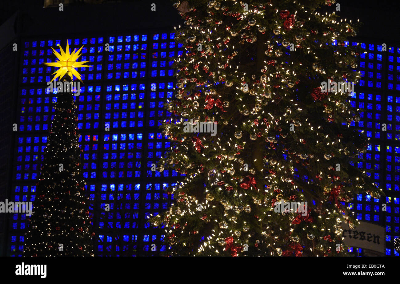 Berlin, Deutschland. 22. November 2014. Eine verzierte Christmas tree (R) beleuchtet auf dem Weihnachtsmarkt an der Kaiser-Wilhelm-Gedächtniskirche in Berlin, Deutschland, 22. November 2014. Die neuen Gedächtniskirche leuchtet blau hinter die Weihnachtsbäume. Viele Weihnachtsmärkte eröffnen am Montag in der Hauptstadt. Foto: Rainer Jensen/Dpa/Alamy Live-Nachrichten Stockfoto