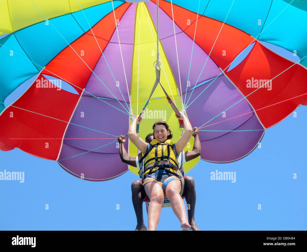 Eine Frau mittleren Alters in ihren 50ern, parasailing oder Drachenfliegen, mit Hilfe, Mauritius Stockfoto