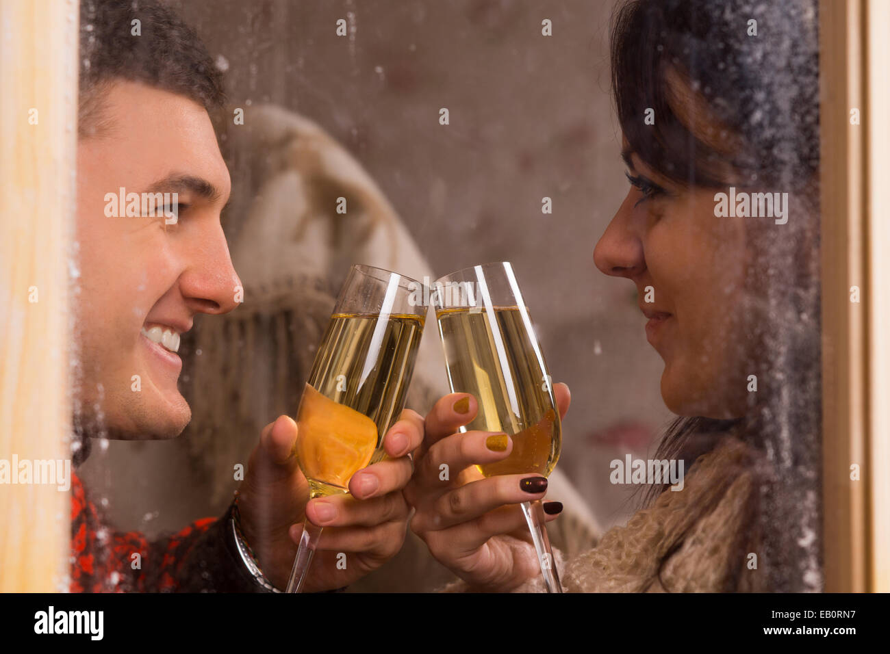 Blick durch mattierte Fensterscheiben von einer jungen Sweethearts mit Champagner klirrende Gläser zu feiern, wie sie in jeder Oth Lächeln Stockfoto