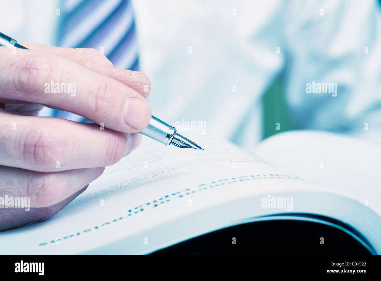 Eine Hand mit einem Füllfederhalter und etwa Schriftsteller eine Notiz oder markieren Sie einen Text zur Korrektur. Stockfoto