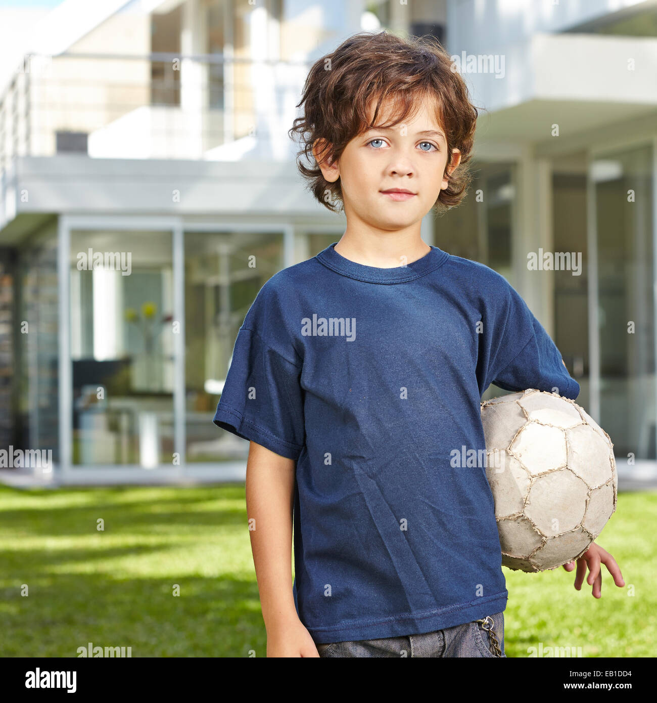 Junge mit seinem Fußball in einem Garten vor einem Haus stand Stockfoto