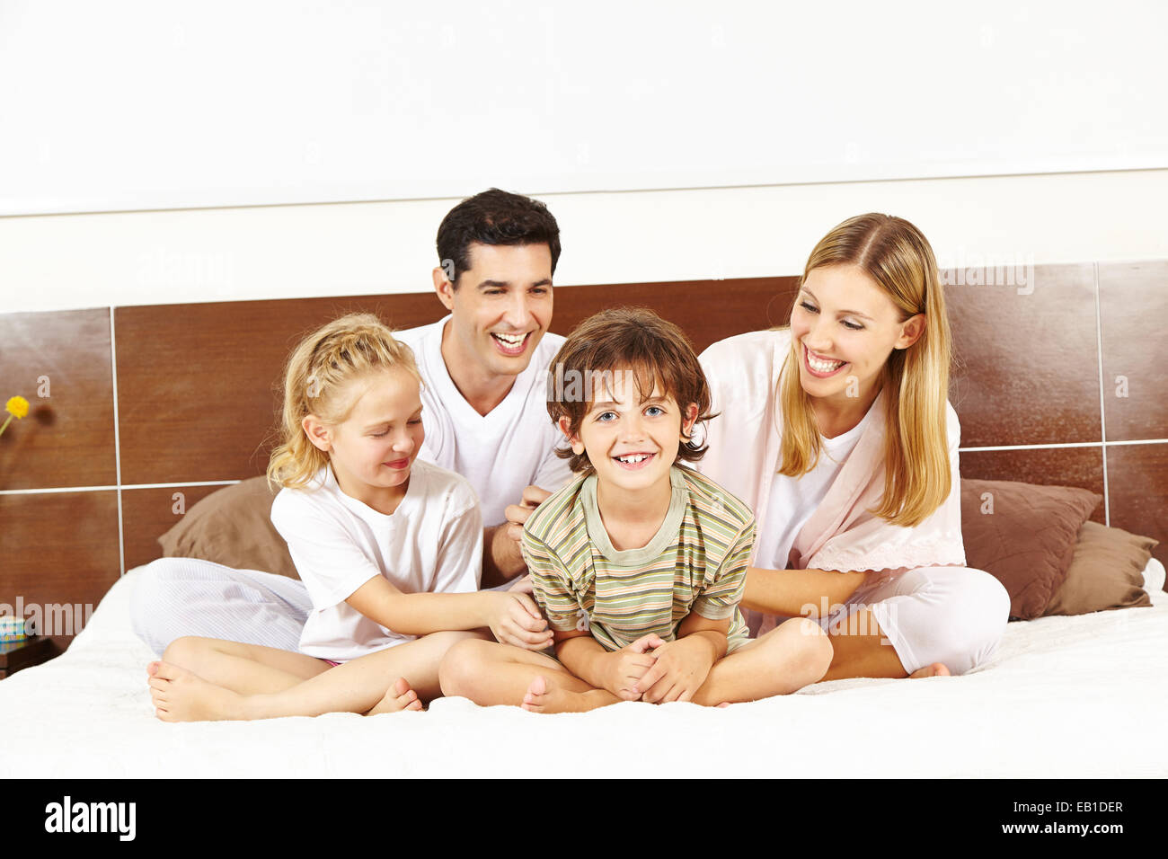 Glückliche Familie mit zwei Kindern sitzen im Bett in den Morgen Stockfoto
