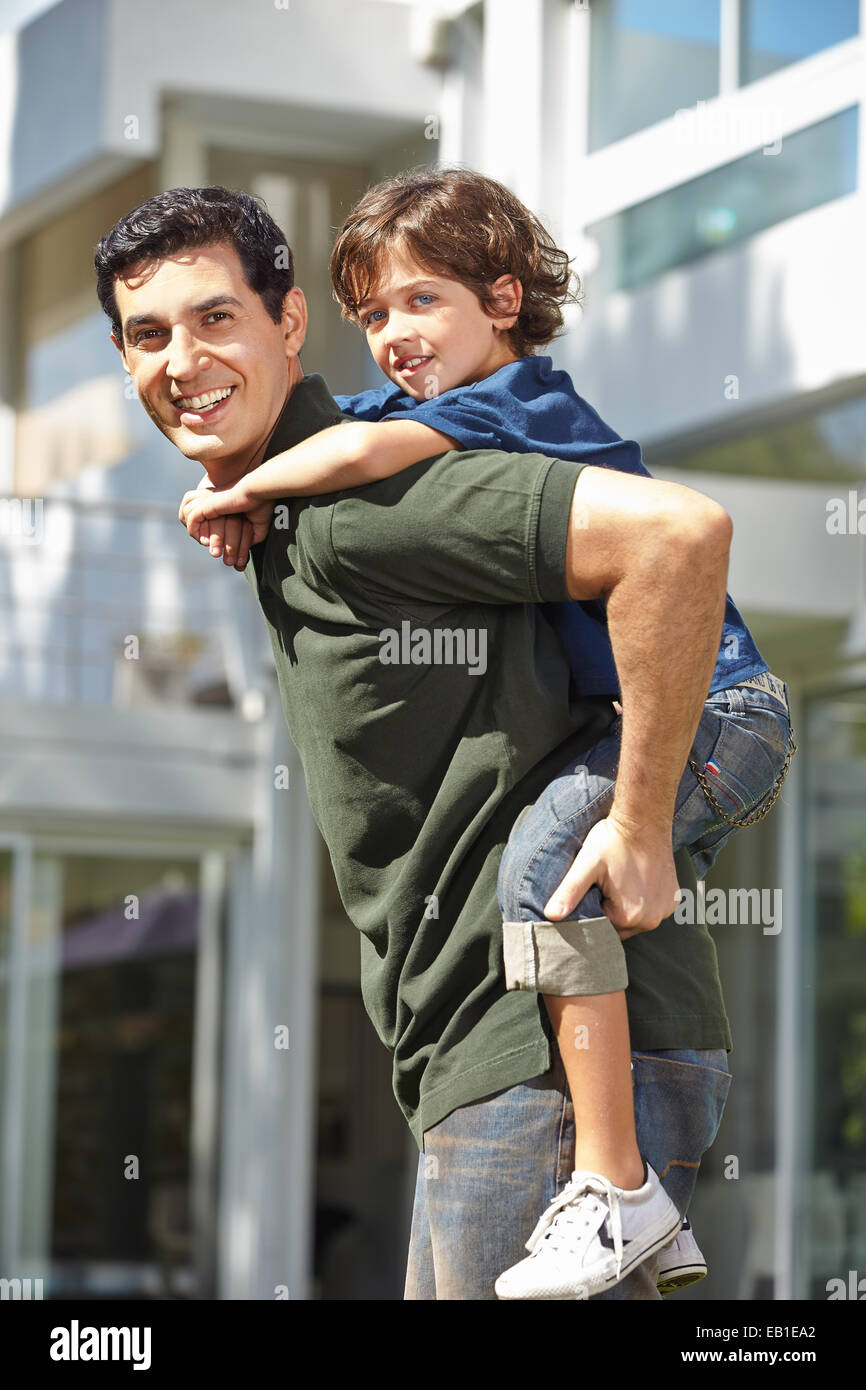 Glücklicher Vater mit seinem Sohn auf dem Rücken für eine Huckepack Fahrt Stockfoto