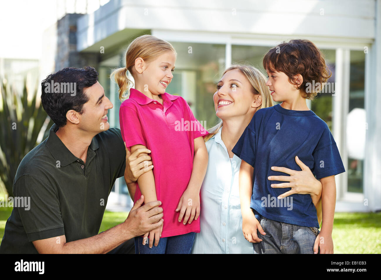 Glückliche Familie mit zwei Kindern im Garten eines Hauses lachen Stockfoto
