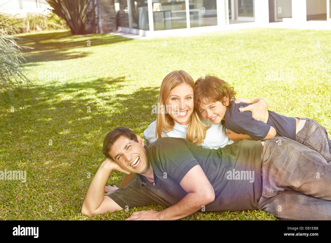 Glückliche Familie mit einem Kind im Garten vor einem Haus verlegen Stockfoto