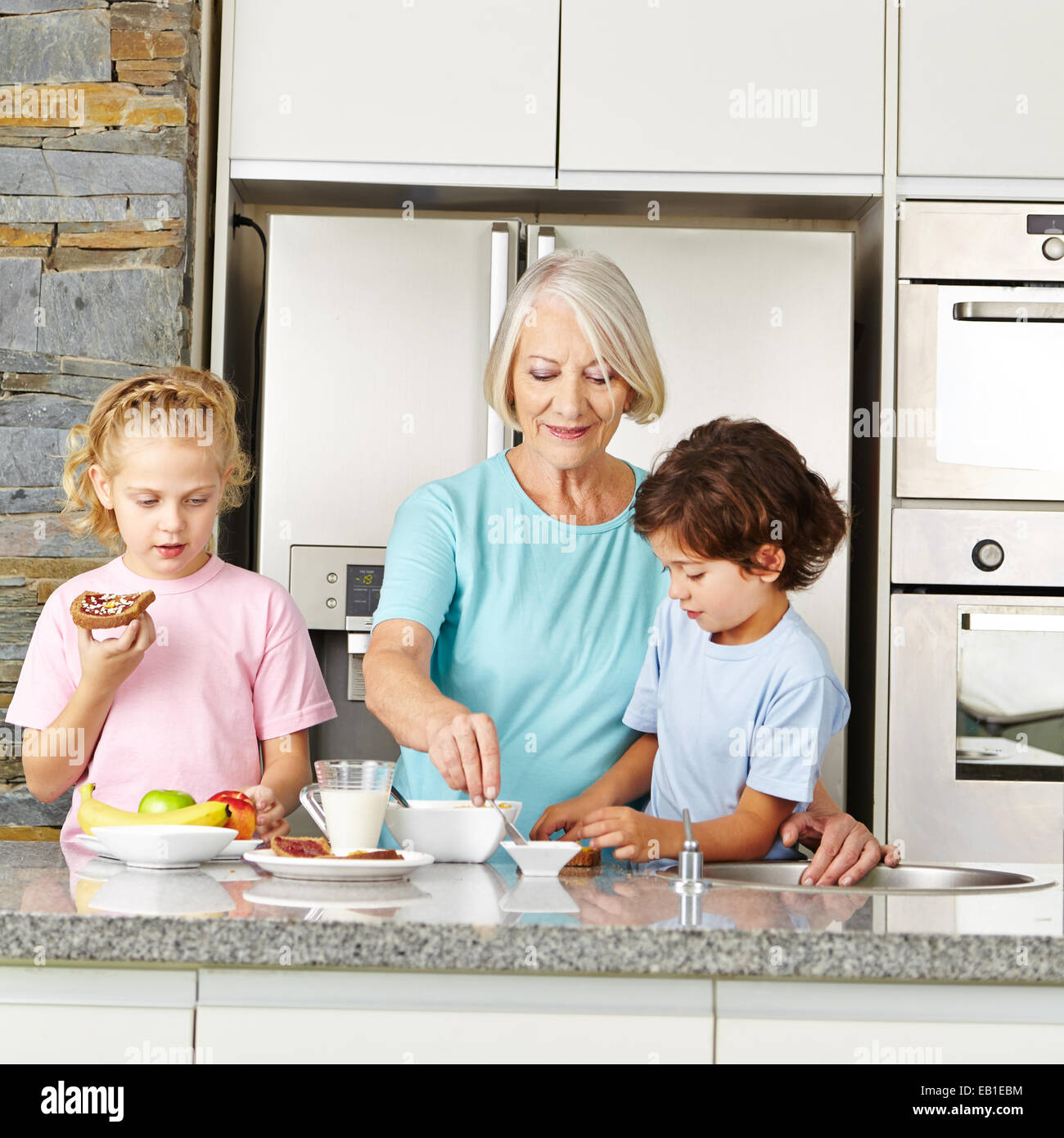 Großmutter, ihre zwei Enkel in der Küche ein gesundes Frühstück vorbereiten Stockfoto