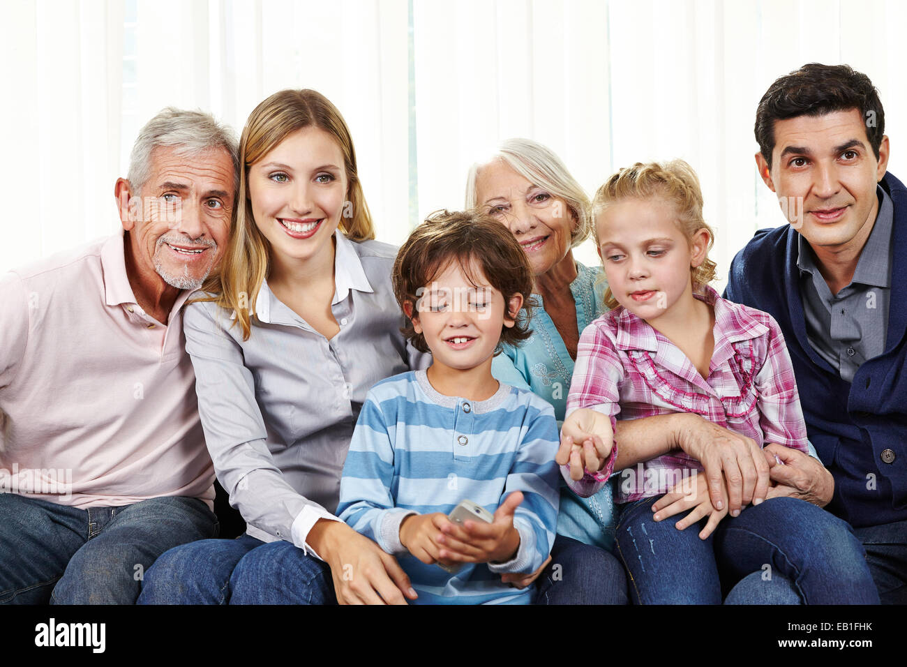 Familie vor dem Smart Fernseher mit Fernbedienung im Wohnzimmer Stockfoto