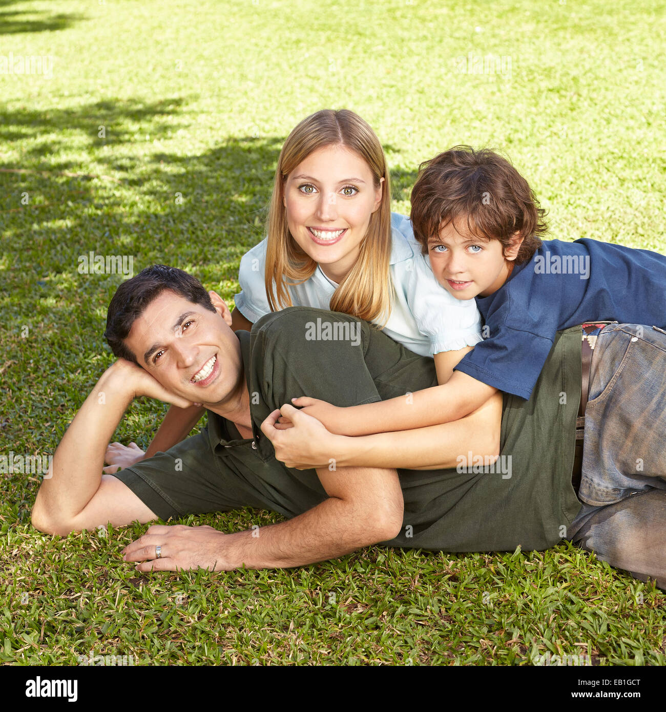 Glückliche Familie mit Sohn Verlegung im Sommer Gras eines Gartens Stockfoto