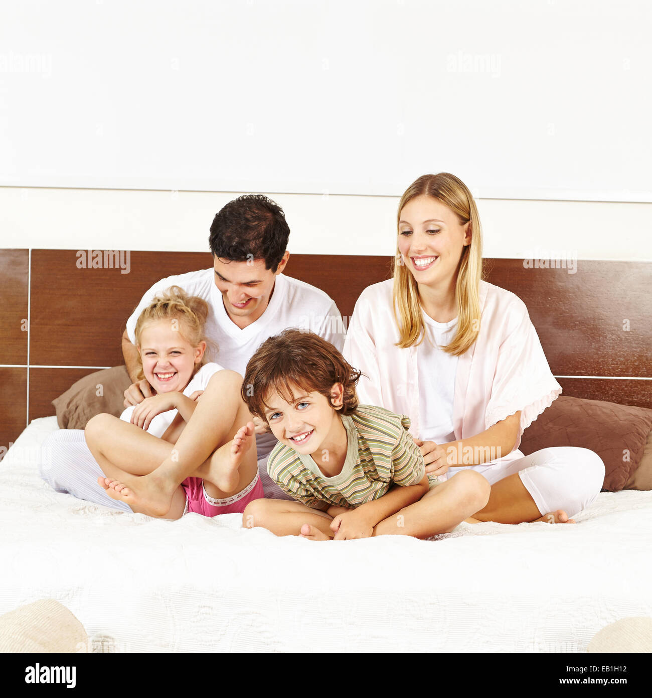 Lachende Familie Spaß mit Kindern auf Bett in einem Schlafzimmer Stockfoto