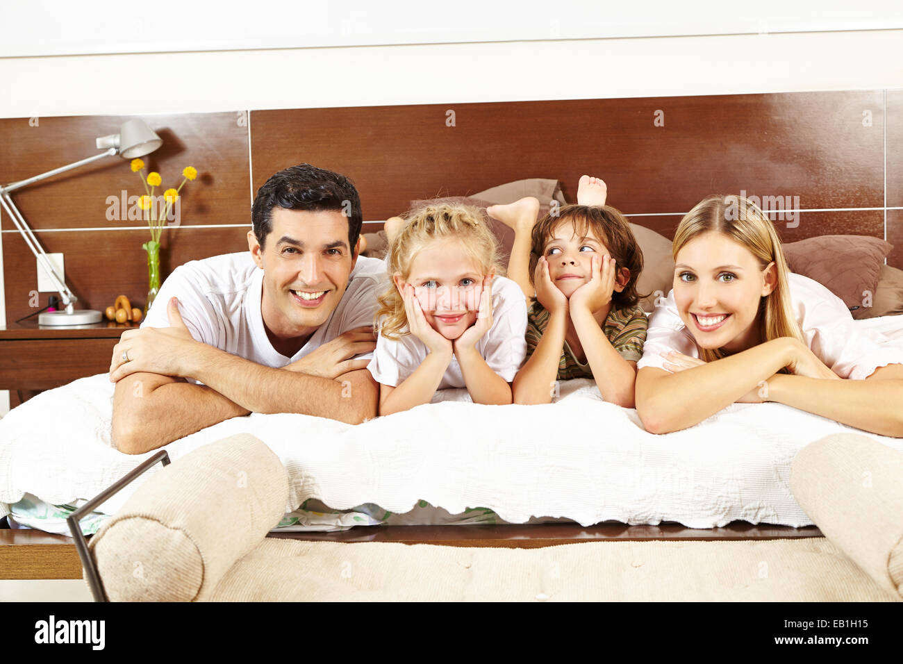 Glückliche Familie mit zwei Kindern mit zusammen auf Bett im Schlafzimmer Stockfoto