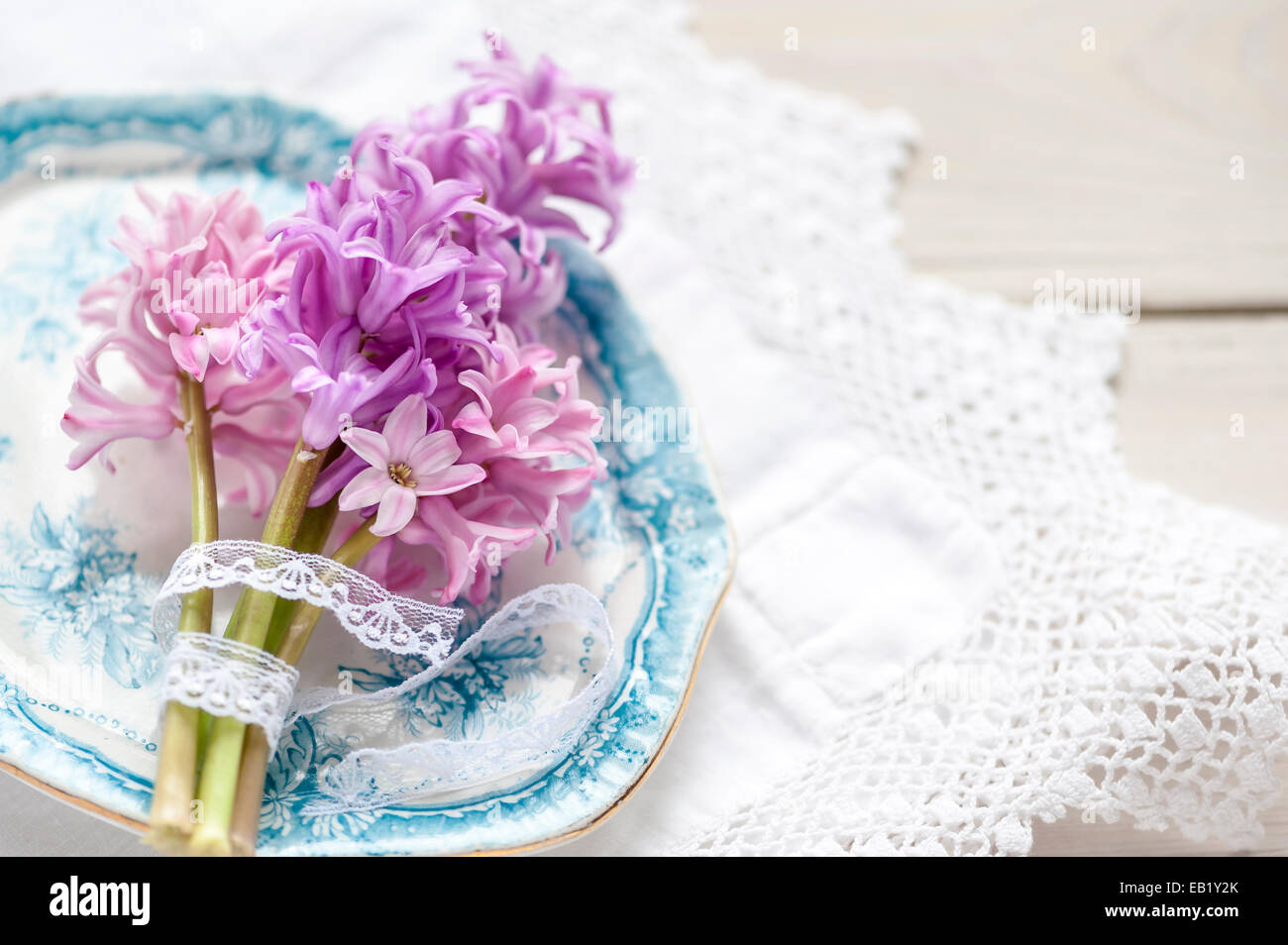 Posy rosa Hyazinthen auf Vintage blaue Platte auf Spitzen Tischdecke erschossen von oben Stockfoto